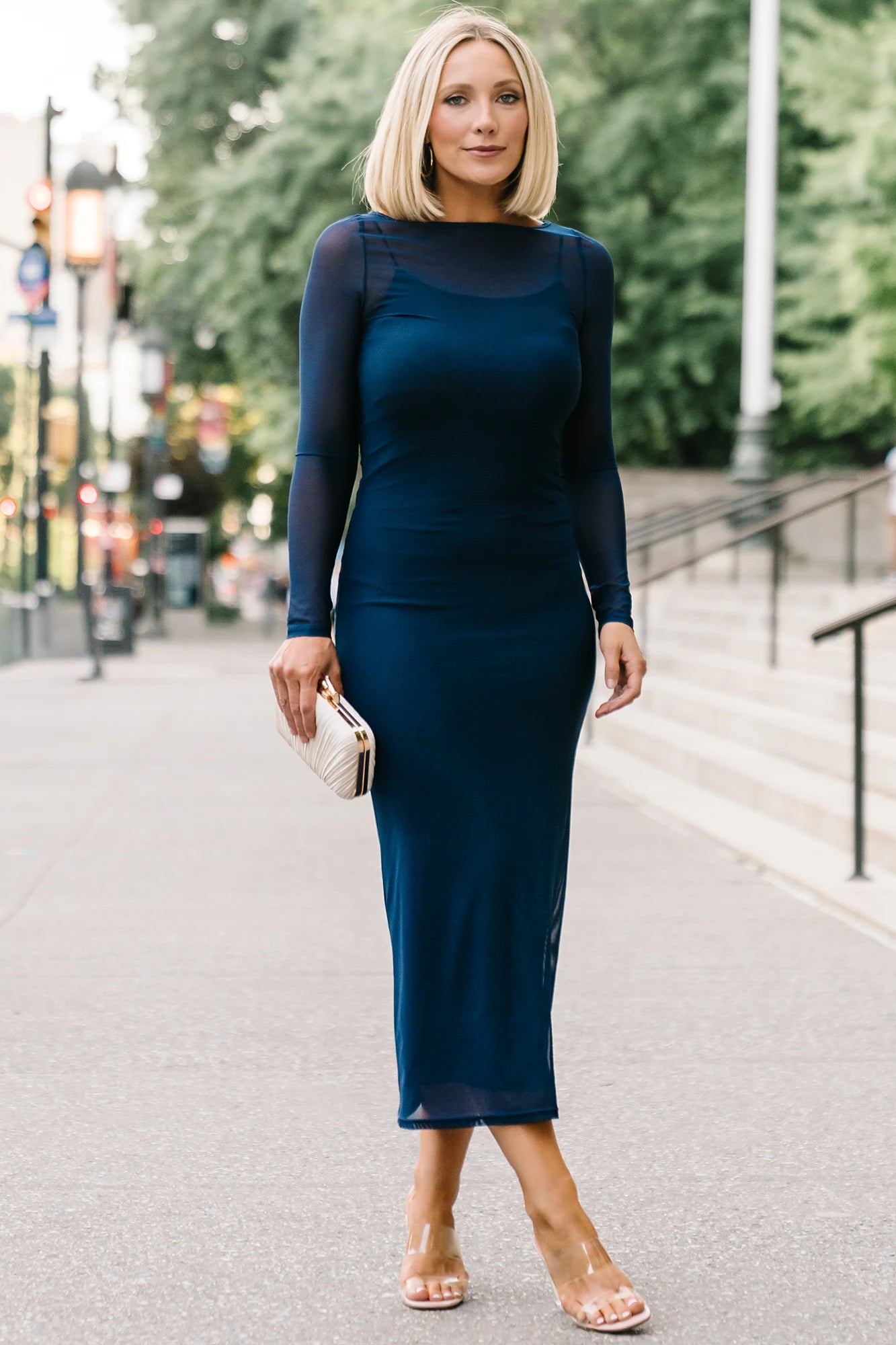 Model wearing the Darya Mesh Midi Dress in Navy featuring a sheer mesh overlay with a round neckline, long sleeves, and a fitted bodycon midi silhouette layered over a matching ribbed slip.