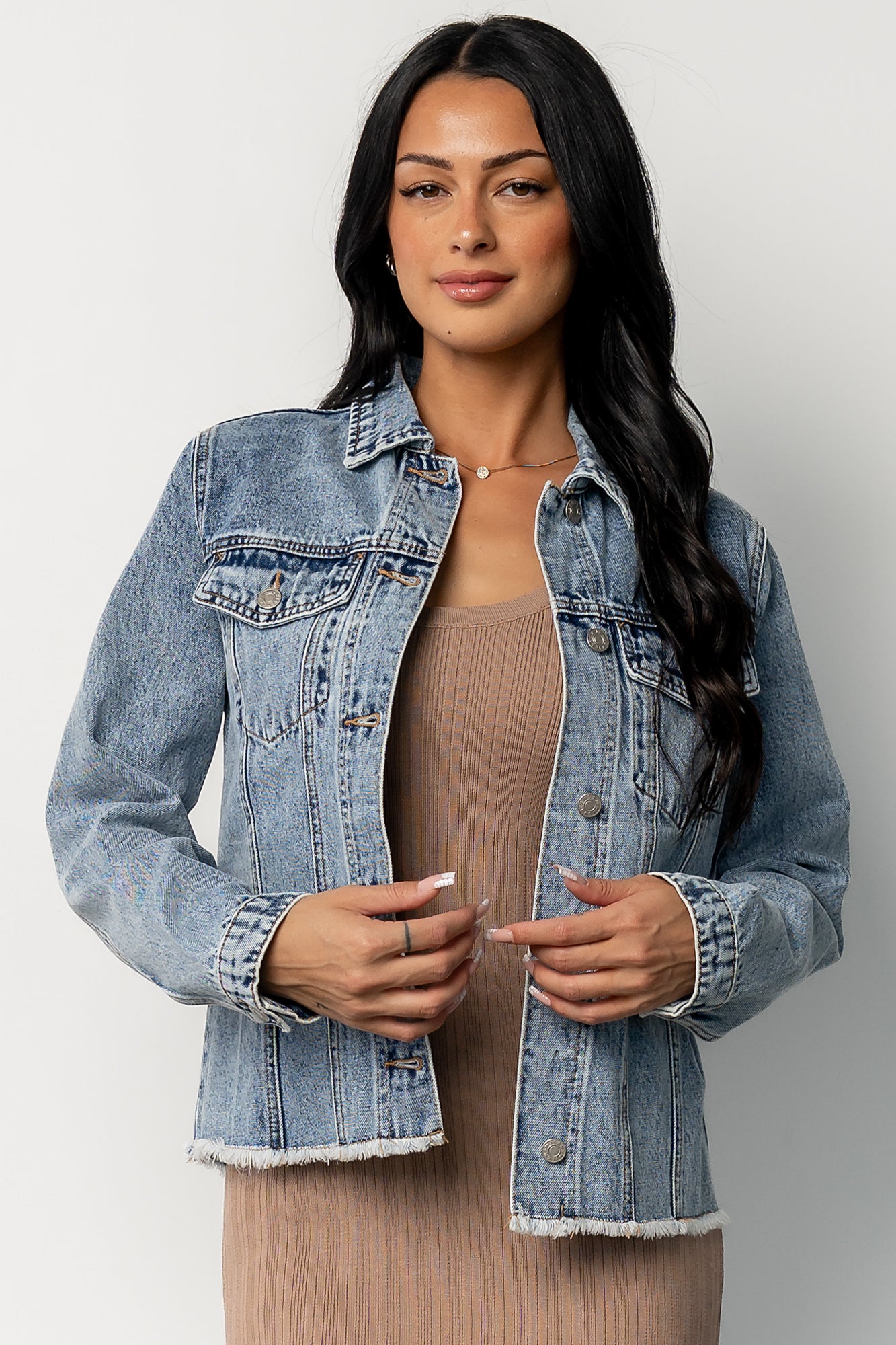 Front view of model wearing a light-wash Devon denim jacket showing relaxed fit, collared neckline, patch pockets, and frayed hem.