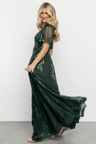 Three-quarter side view of the Karina sequin maxi dress on model, highlighting princess seams, mesh drape, and elegant skirt movement.