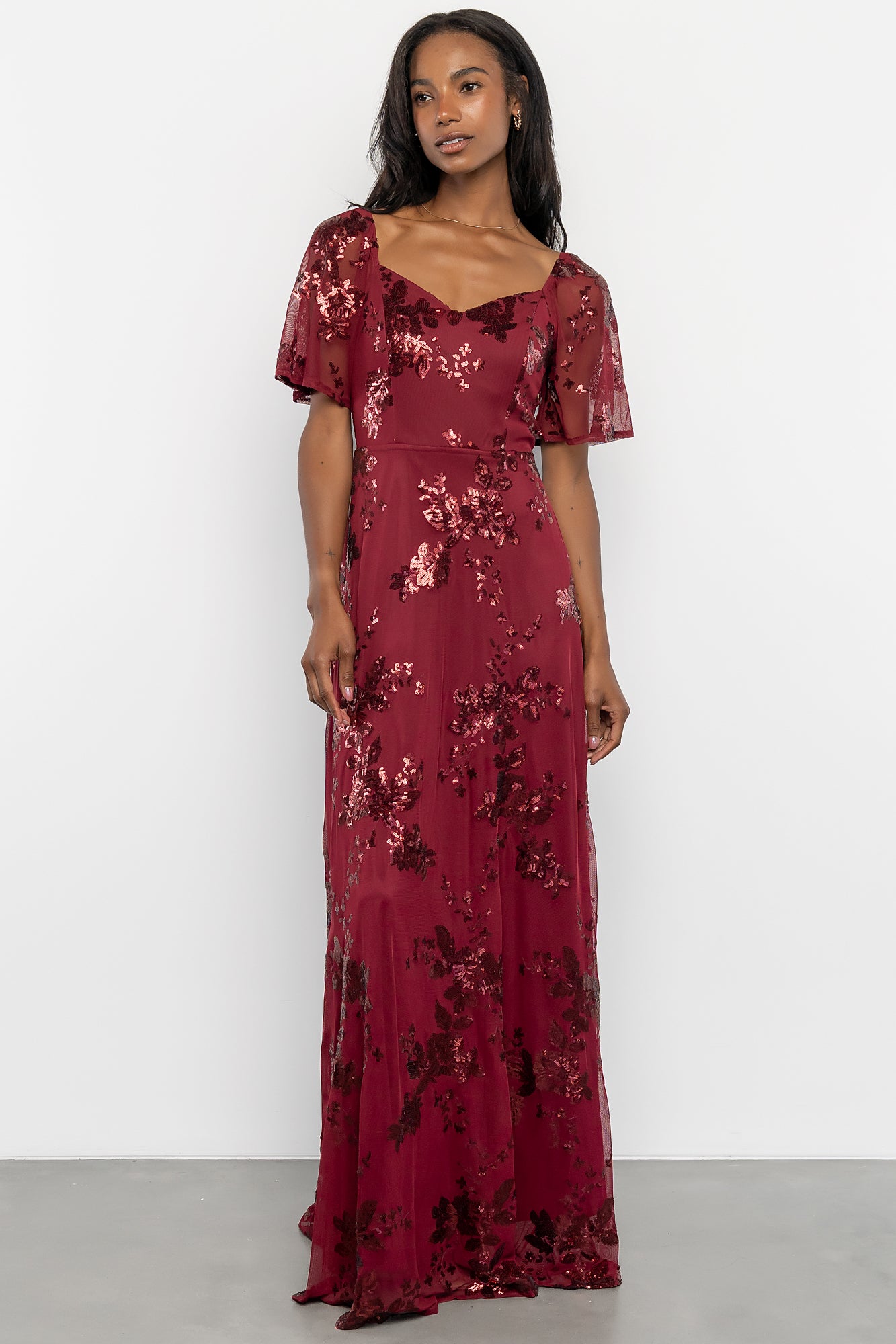 Styling shot of Karina sequin maxi dress in wine paired with heels, showcasing overall length, movement, and formal styling options.