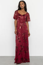 Styling shot of Karina sequin maxi dress in wine paired with heels, showcasing overall length, movement, and formal styling options.