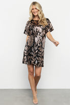Model wearing Squires sequin short dress in black with rose-gold floral sequins, short skirt length and keyhole back detail.