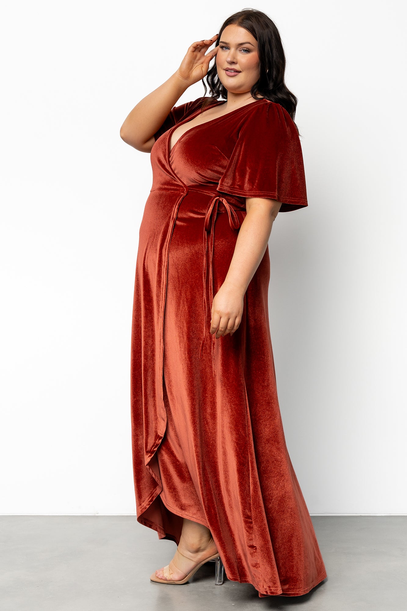 Full-length candid shot of the Cinnamon velvet Katelyn wrap dress in motion; shows side wrap tie, tulip hem opening and soft stretch of fabric.