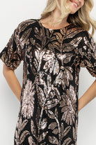 Back view showing keyhole with button closure at back neck and sequin coverage down the short skirt silhouette.