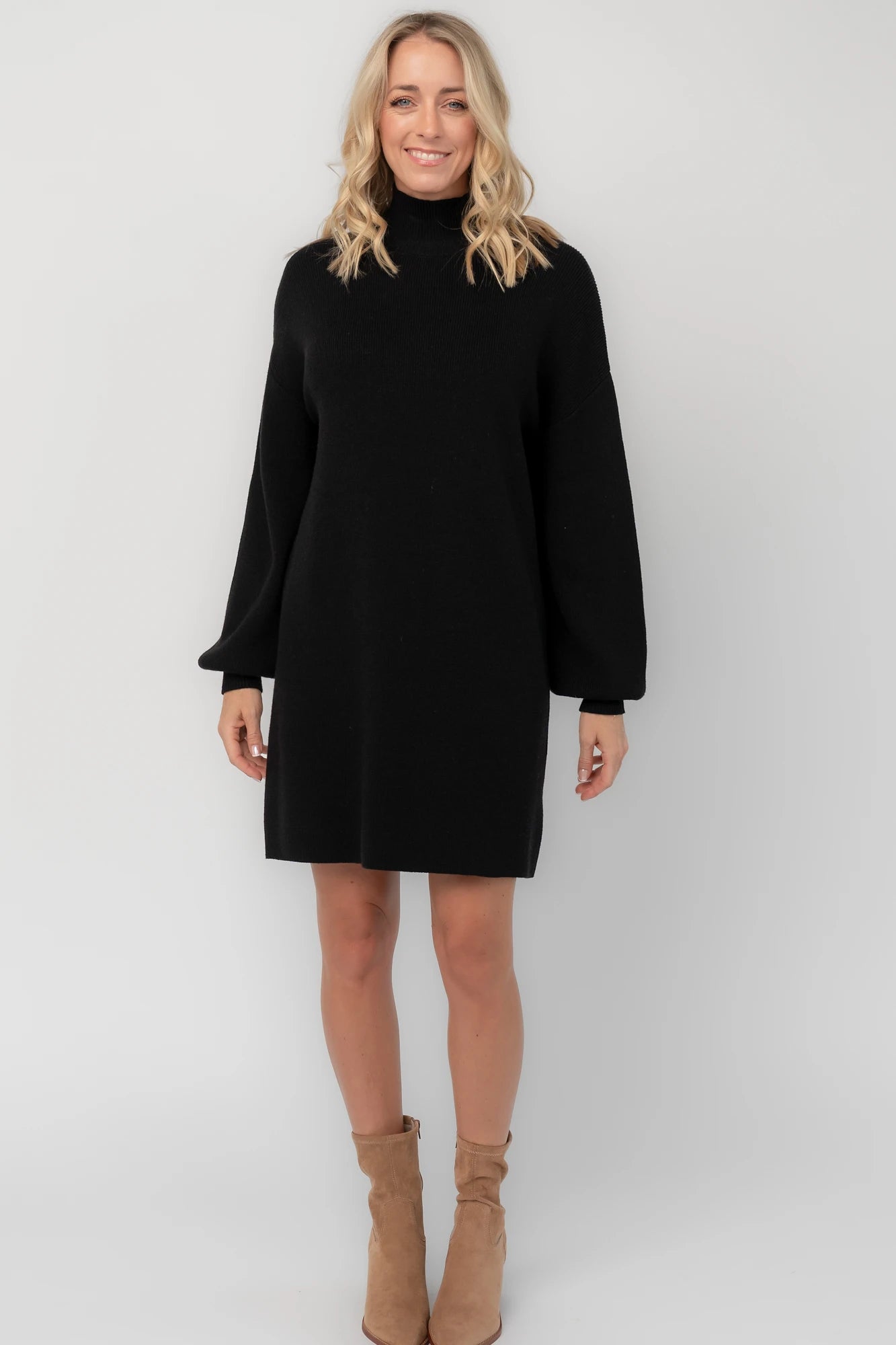 Black knit sweater dress with a mock neckline, long balloon sleeves, dropped shoulders, and a relaxed above-the-knee silhouette.