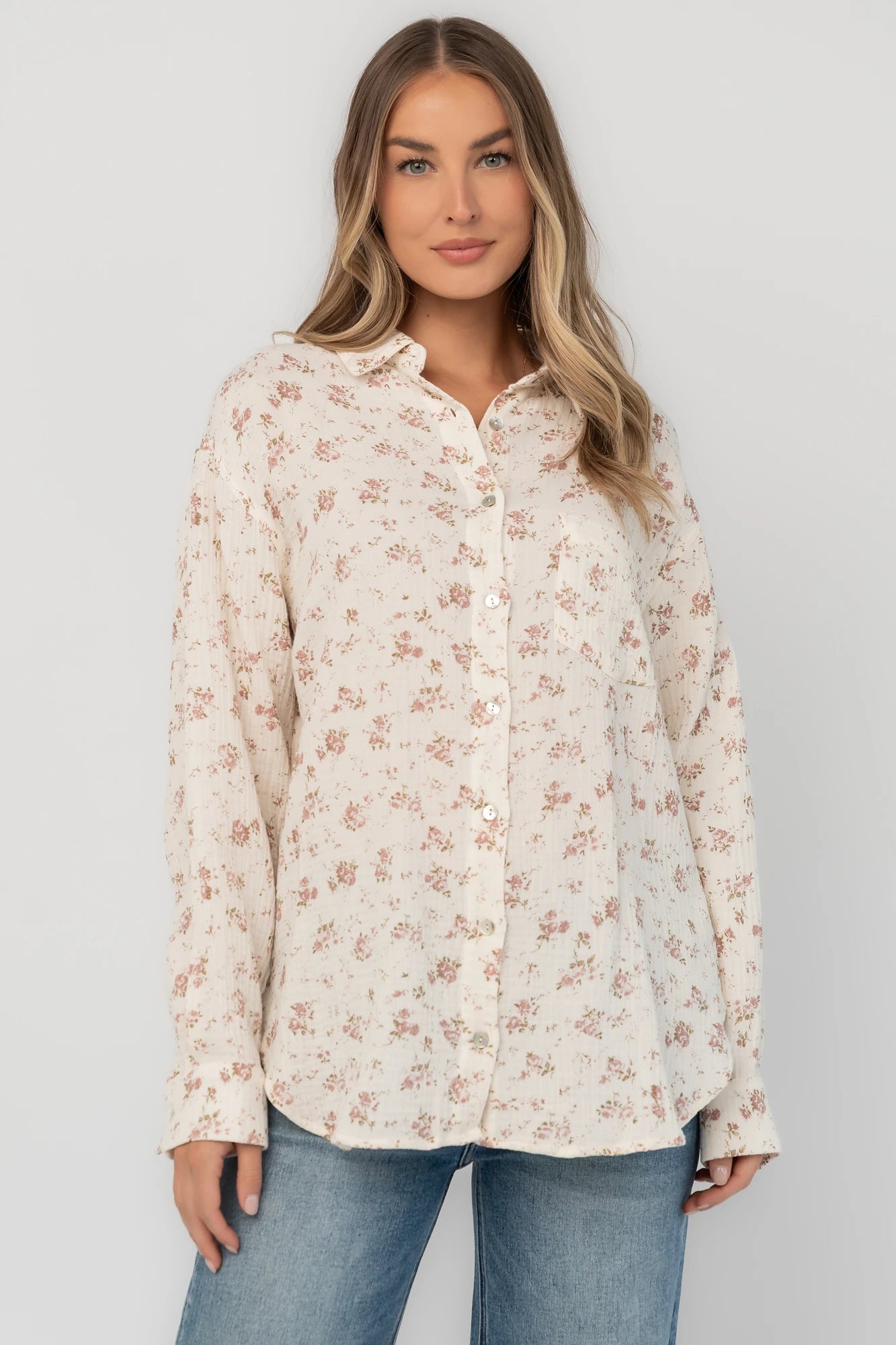 Ivory floral button-front blouse with a collared neckline, long sleeves, front patch pocket, relaxed oversized fit, and rounded high-low hem.