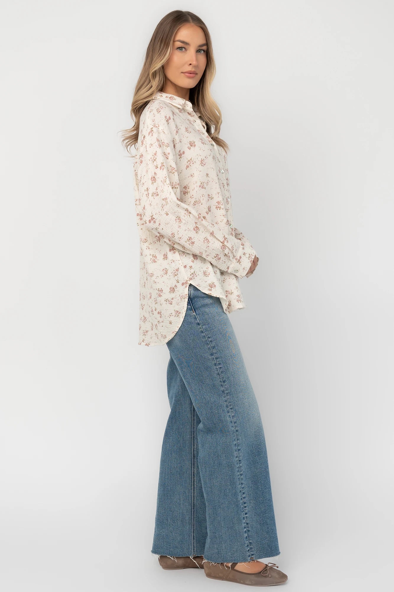 Ivory floral button-front blouse with a collared neckline, long sleeves, front patch pocket, relaxed oversized fit, and rounded high-low hem.