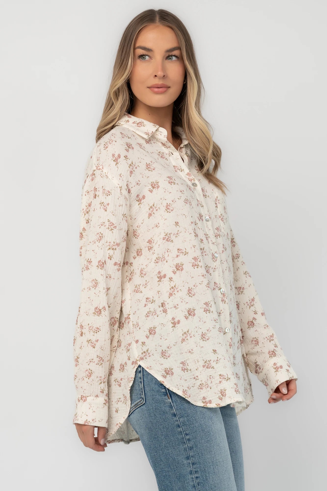 Ivory floral button-front blouse with a collared neckline, long sleeves, front patch pocket, relaxed oversized fit, and rounded high-low hem.