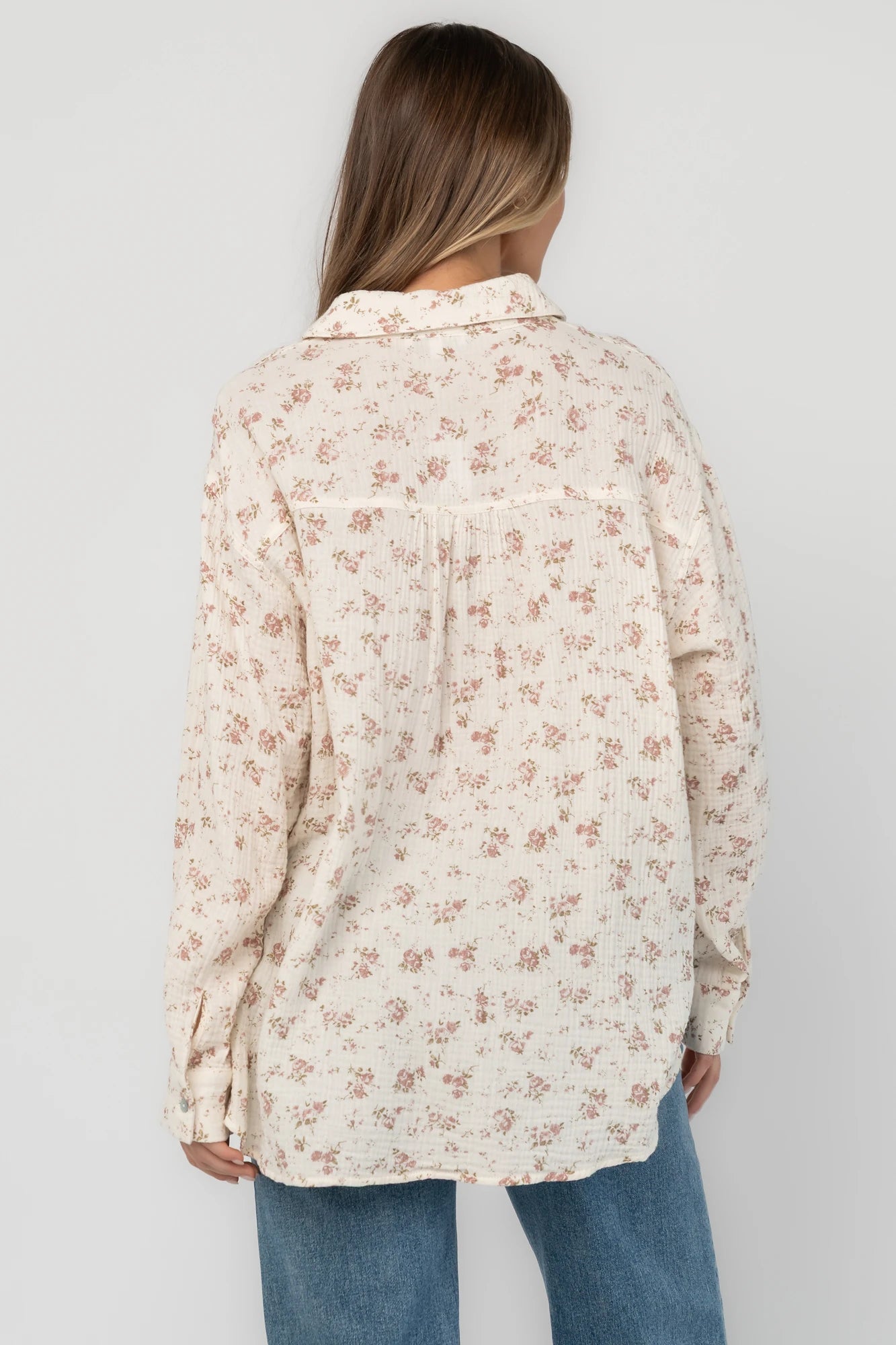 Ivory floral button-front blouse with a collared neckline, long sleeves, front patch pocket, relaxed oversized fit, and rounded high-low hem.