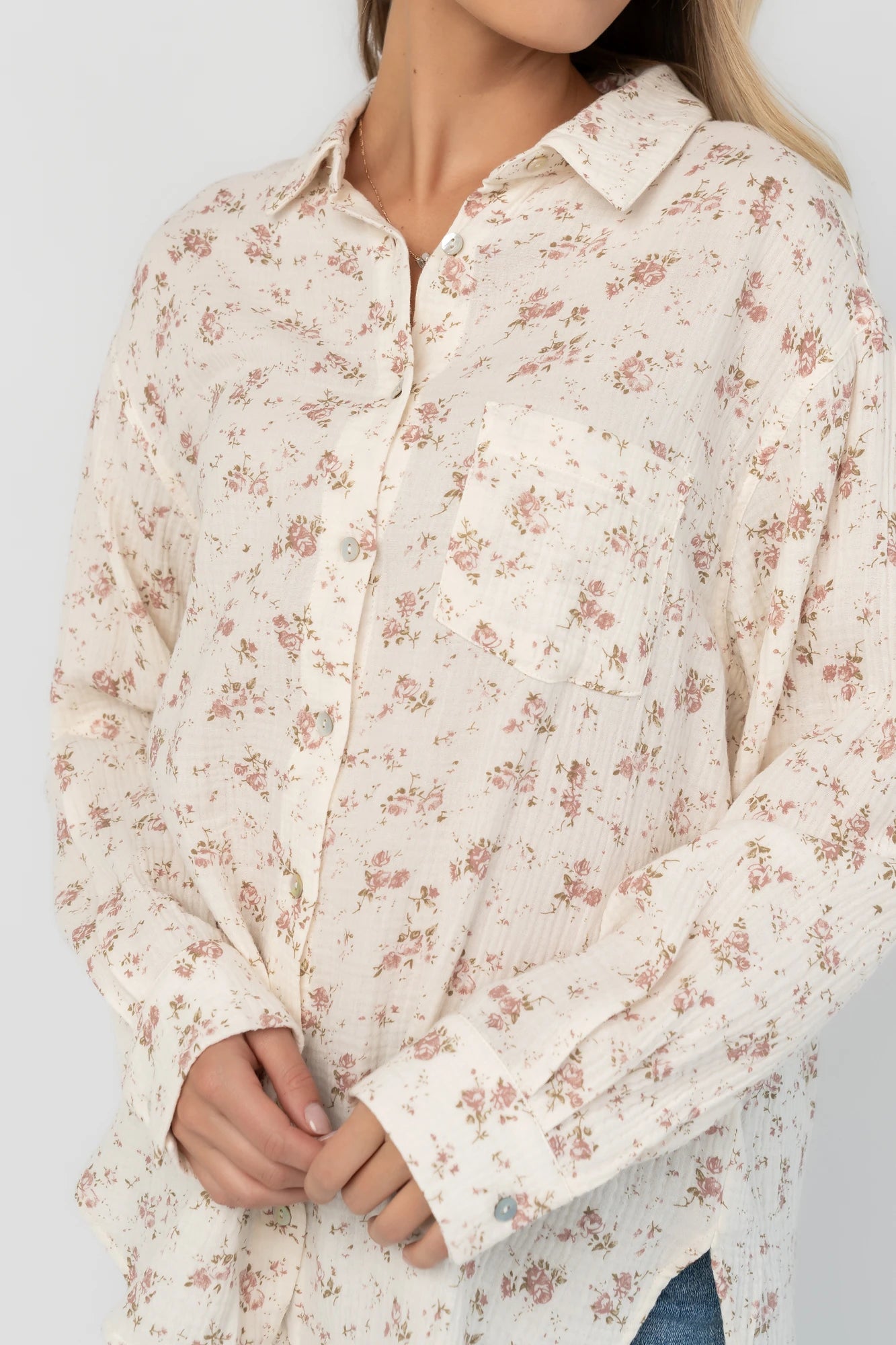 Ivory floral button-front blouse with a collared neckline, long sleeves, front patch pocket, relaxed oversized fit, and rounded high-low hem.