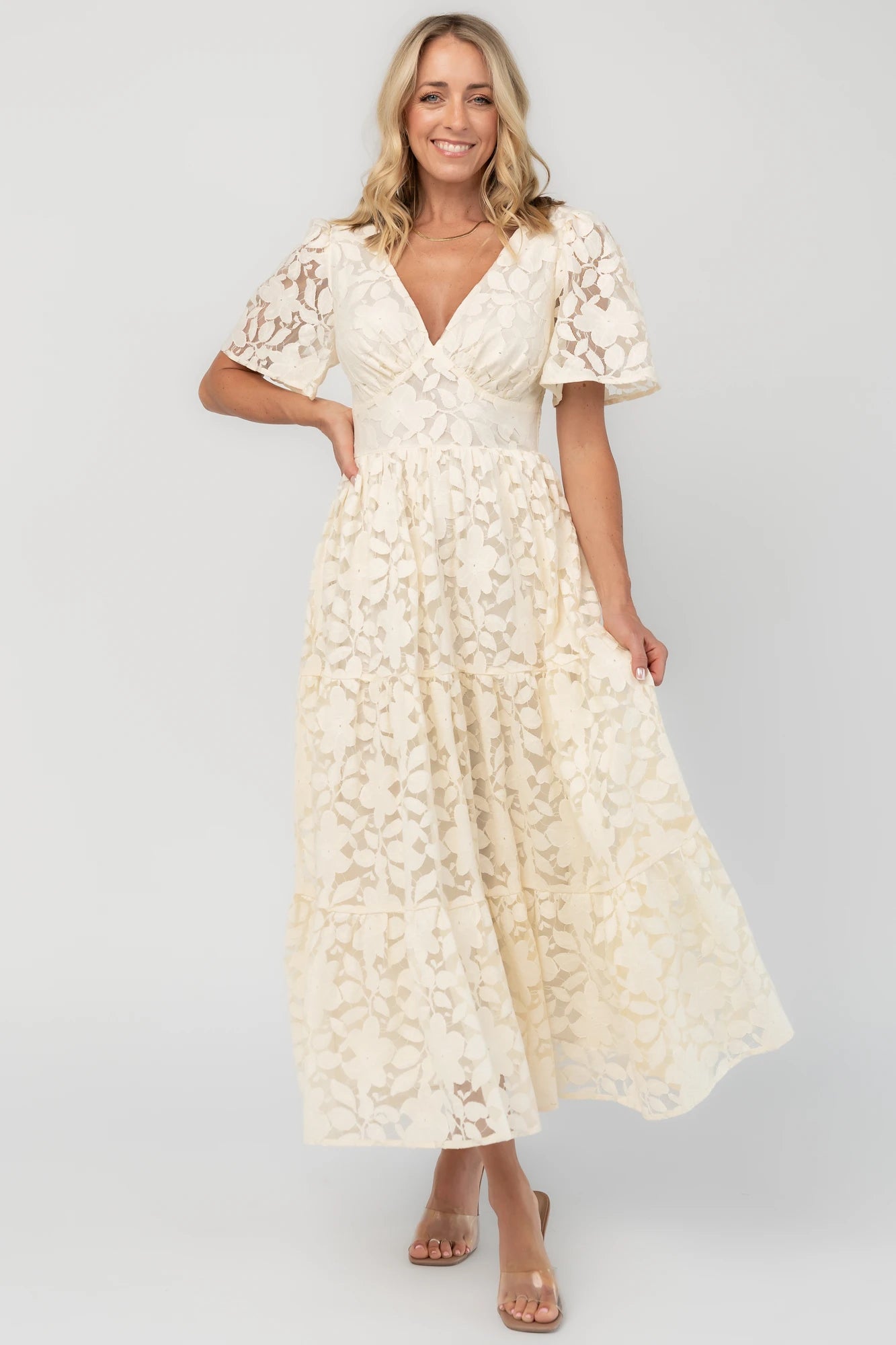 Floral lace midi dress with a deep V-neckline, short flutter sleeves, smocked back bodice, defined waistband, and tiered skirt.