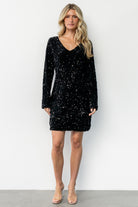 Styled look of Mira black sequin dress on model with accessories, illustrating proportion, V-neckline, and party styling.