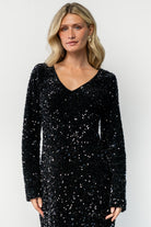 Three-quarter side view of the Mira black sequin dress showing straight fit silhouette, long sleeve detail, and short skirt length.