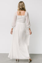 Back view of white Giselle maxi dress showing smocked back, unlined airy sleeves, and a long flowing silhouette.