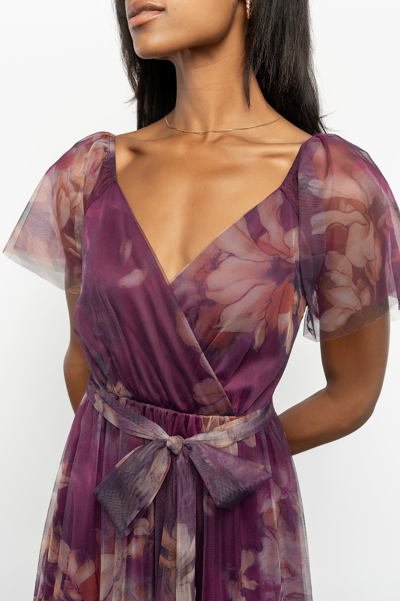 Close-up of aubergine floral print and delicate tulle overlay over smooth lining, showing fabric texture and print detail.
