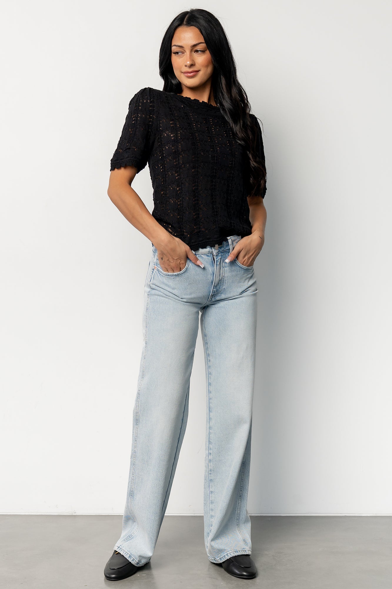 Model wearing Serenity Knit Sweater Top in black styled with a midi skirt, showing how the cropped length and scalloped details finish an outfit.