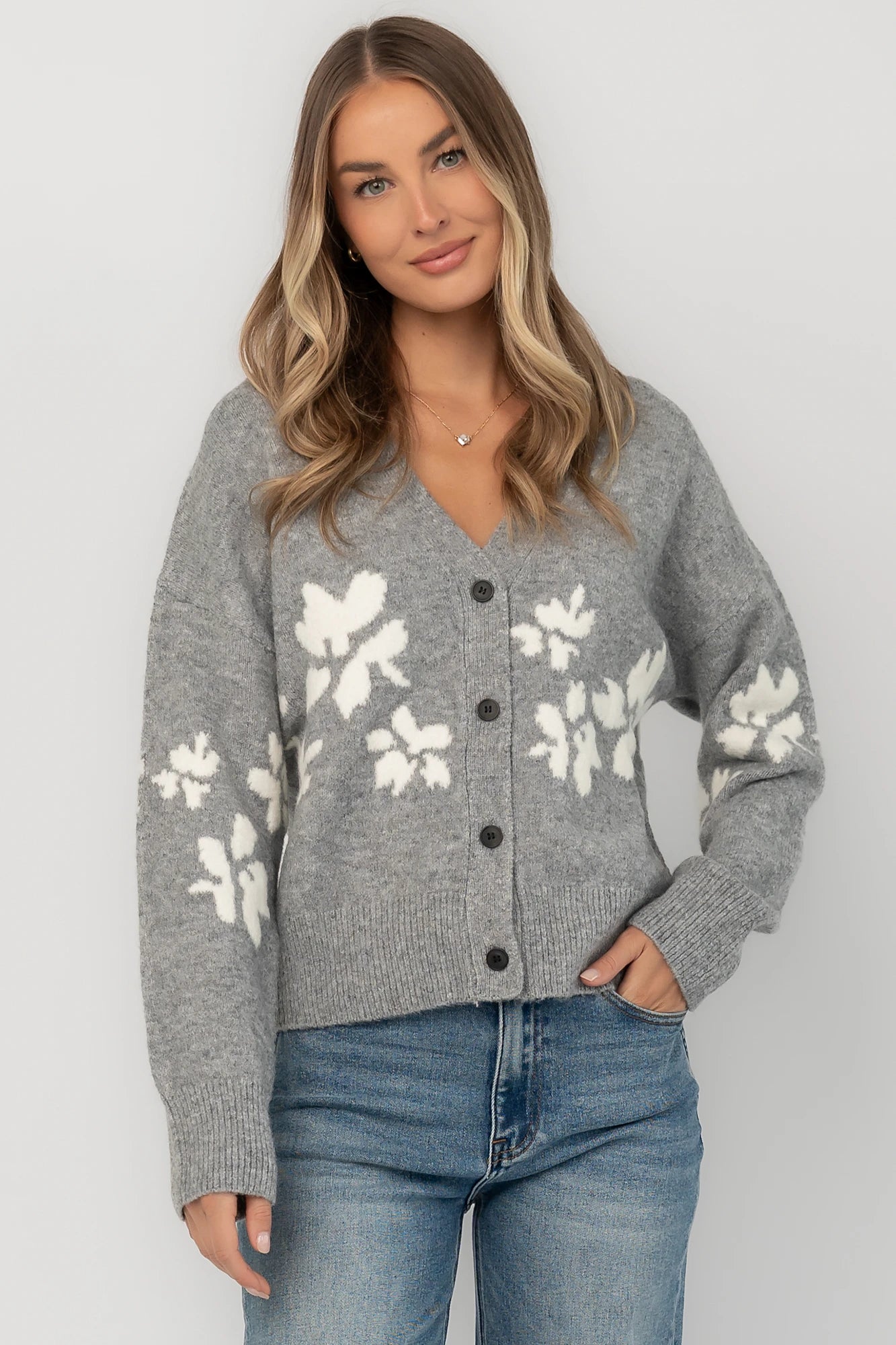 Gray floral knit cardigan with a V-neckline, button-front closure, long sleeves, ribbed trim, and a relaxed silhouette.