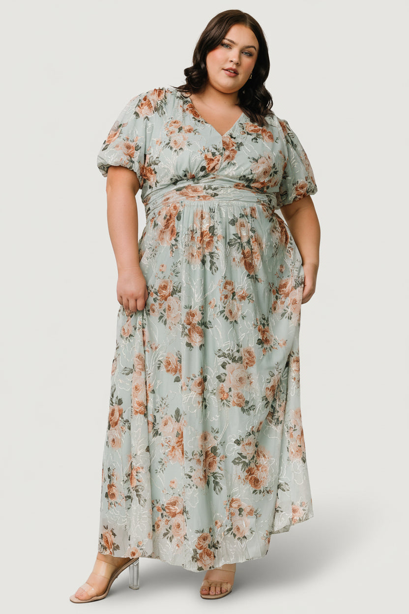 Close-up of embroidered mesh overlay highlighting gold and cream threadwork and muted coral and green floral motifs on a soft sage background.