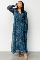 Close-up of deep blue floral chiffon fabric and smocked cuff detail on long sleeve, showing texture and print.