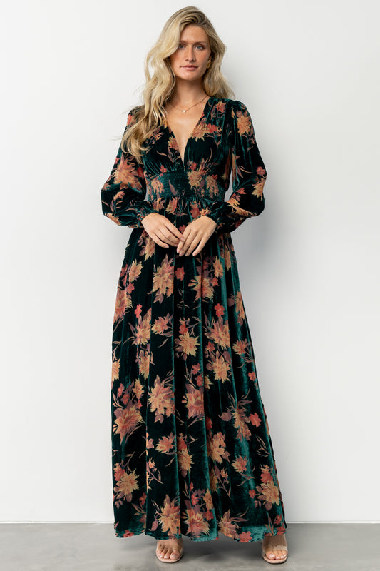 Side angle of the burnout velvet maxi dress showing smocked waistband, lined skirt, and the rich gold, burgundy and spice-toned floral print.