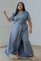 Three-quarter view of whisper blue satin gown highlighting the smooth satin sheen, flowing maxi skirt, and elegant sweep of the hemline.