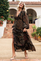 Back view showing elastic back waist, hidden left-side zipper, and long sleeves with elastic cuffs in black multi floral.