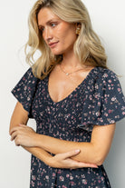 Full-length shot of the Midnight Floral Jerah Dress showing flutter sleeves, empire waist, and relaxed midi silhouette.