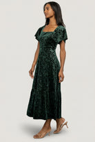 Detailed shot of emerald burnout velvet fabric and floral pattern, showing texture, pile variation, and subtle sheen.