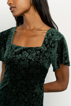 Back view of Eirene burnout velvet maxi dress in emerald, showing seam lines, tiered skirt, and gentle drape.