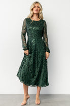 Front view of emerald Kalla sequin midi dress on model, showing A-line silhouette and long sheer sleeves with elastic cuffs.