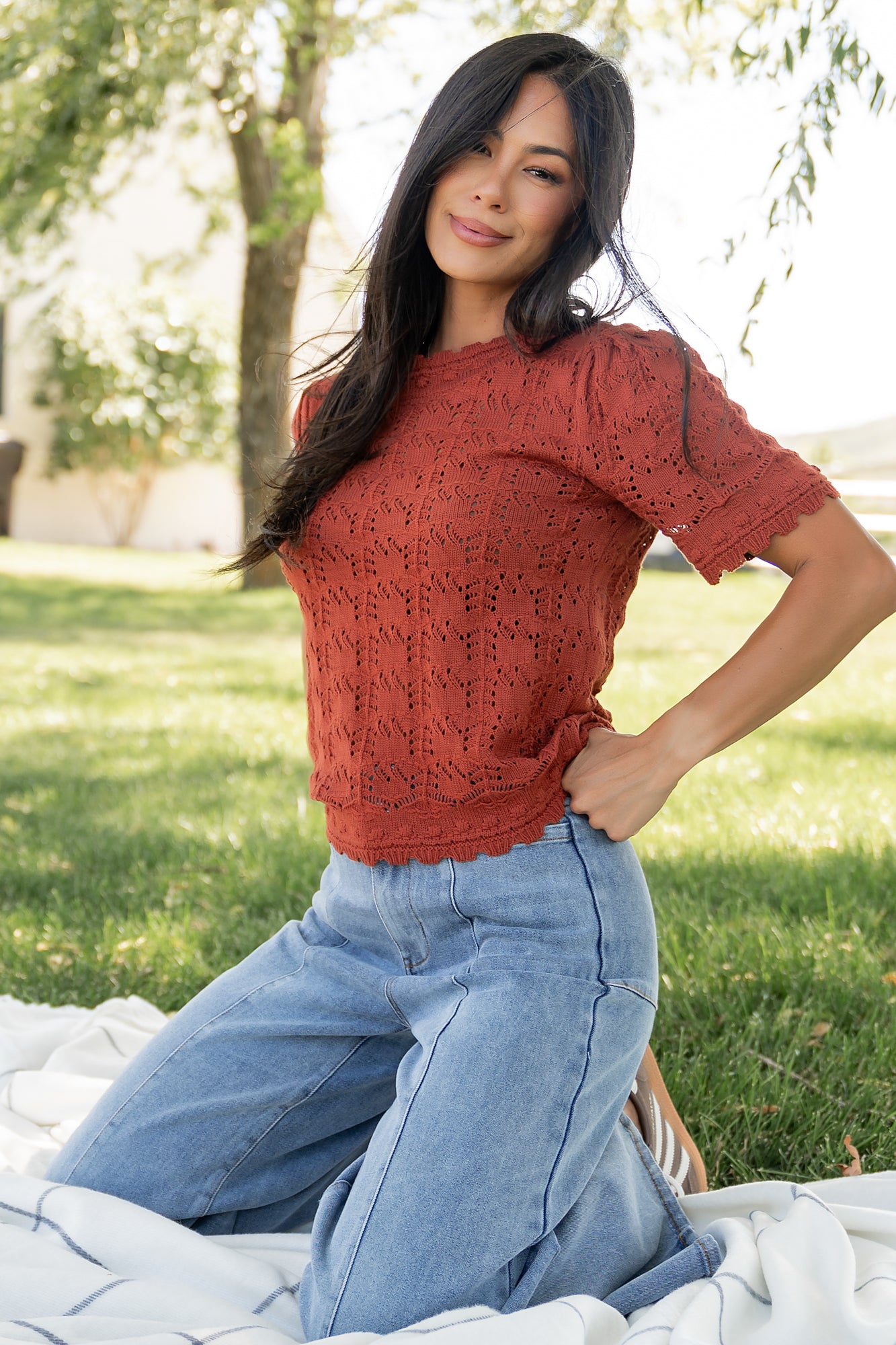 Model wearing Serenity Knit Sweater Top in rust, front view showing scalloped neckline, short sleeves, and open-knit texture.