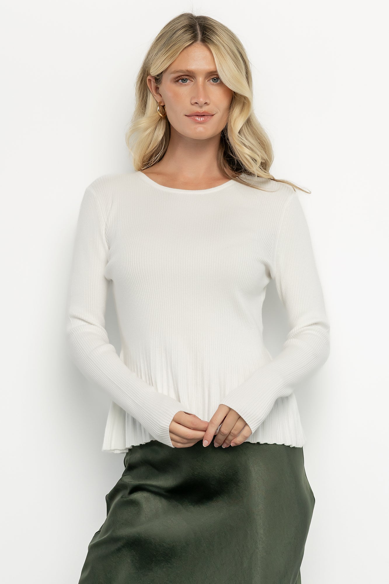 Model wearing off-white Ainsley Ribbed Top with fitted bodice and contrast peplum, styled with jeans for a casual daytime look.