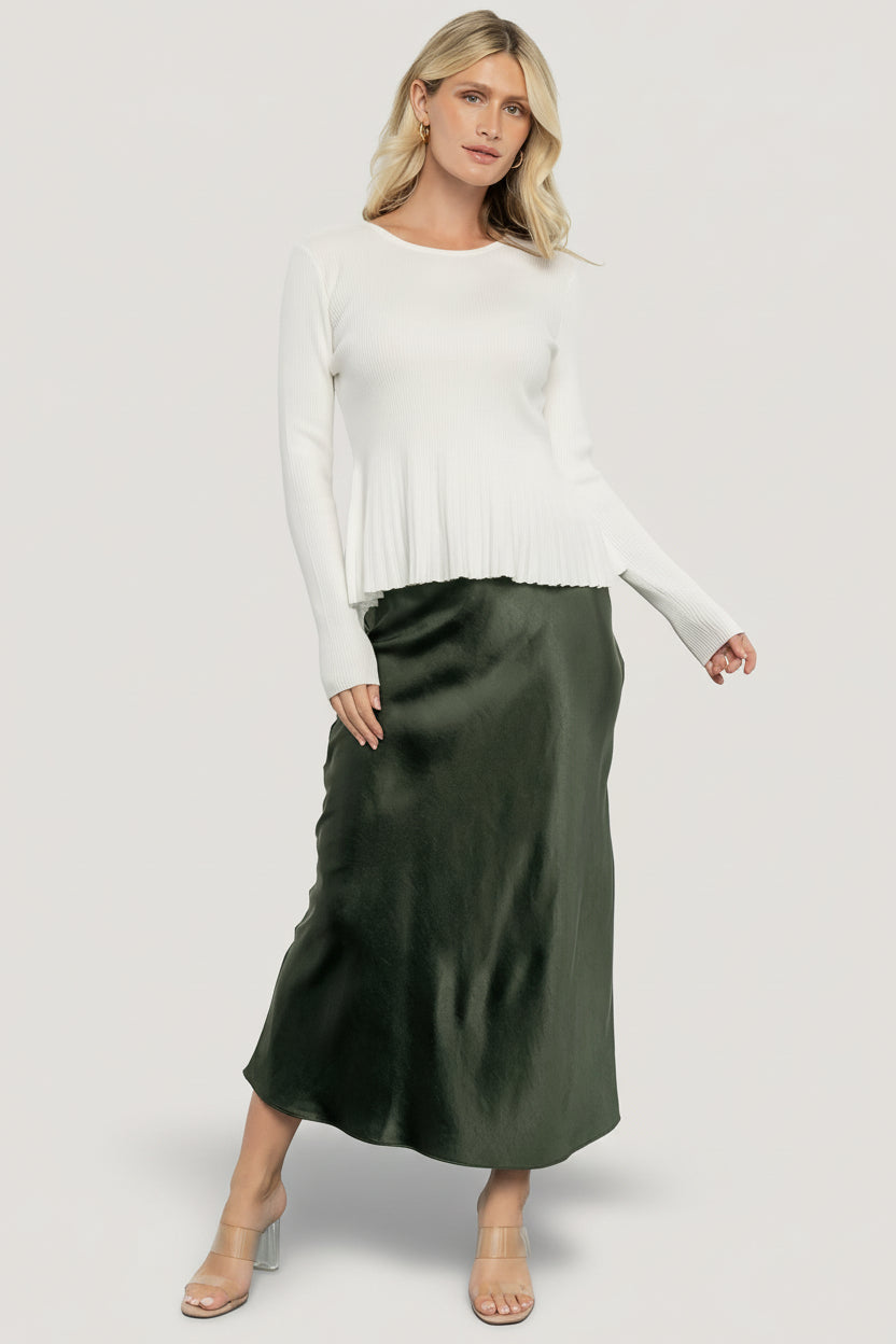 Side view of the Ainsley Ribbed Top in off-white highlighting the contrast ribbed peplum and long sleeve silhouette.
