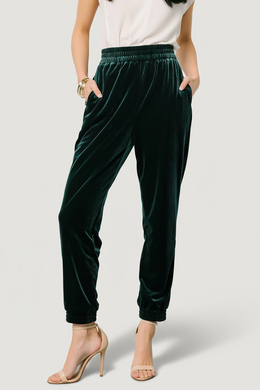 Front model view of Archie velvet jogger pants in dark green, showing elastic waistband, side pockets, and tapered ankle cuff for fit reference.