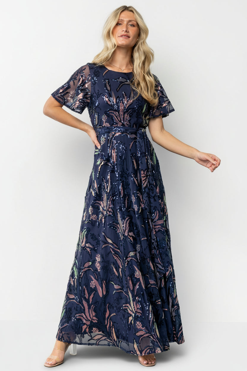 Model wearing Muse Sequin Maxi Dress in dark blue multi on a neutral background, showcasing full length, movement, and sequin embellishment.