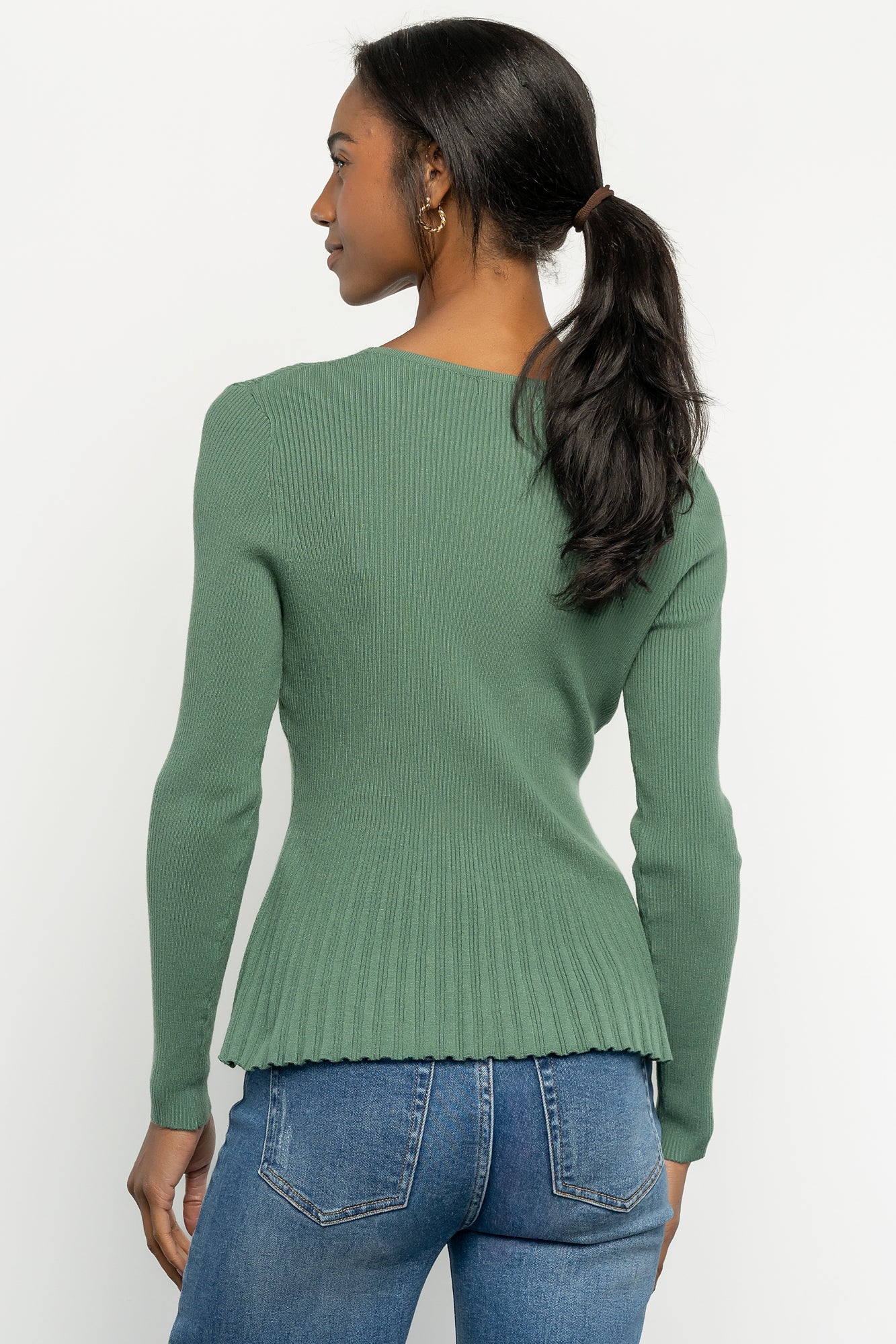 Close-up detail of ribbed knit texture and stitching on the peplum hem, illustrating fabric composition and contrast ribbing.