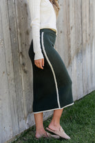 Styled look of the Ava Knit Midi Skirt in dark green paired with boots, demonstrating versatile dressing options for cooler weather.