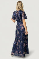 Back view of Muse Sequin Maxi Dress showing keyhole with button closure, waist sash tie, and the flowing maxi silhouette in dark blue multi.