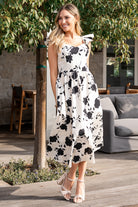 Lifestyle image of the ivory floral midi dress styled with sandals, emphasizing its casual summer-ready silhouette and movement.