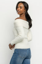 Flat-lay of Perla ivory sweater showing folded foldover neckline, fabric texture, and knot placement.