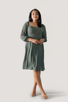 Side view of short chiffon dress in dark sage highlighting lined skirt and airy sleeves with smocked cuffs