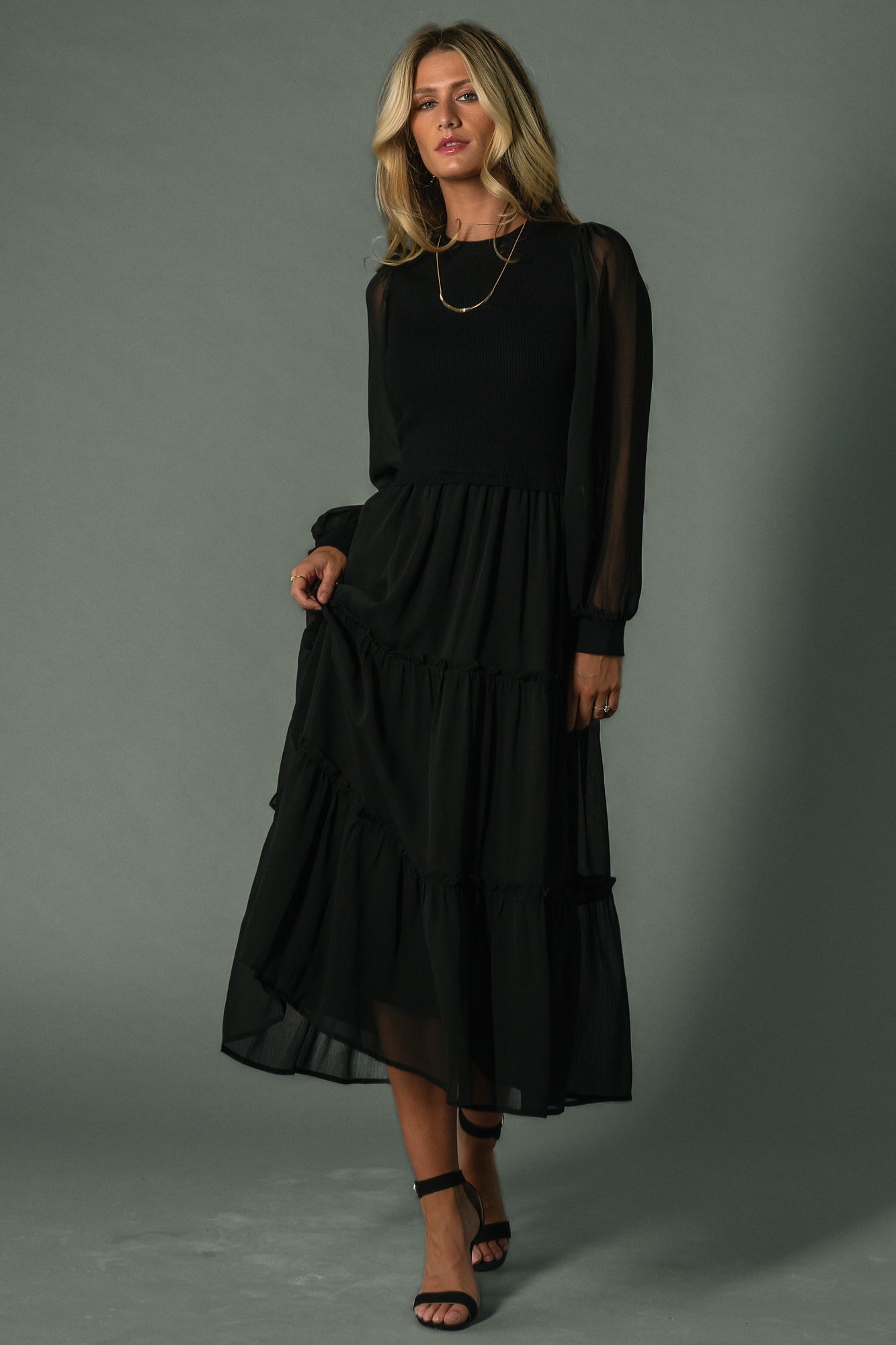 Model wearing Remi ribbed maxi dress in black, side pose highlighting tiered tulle overlay and flowing skirt movement.