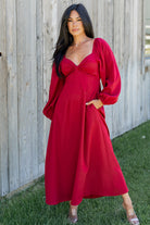 Front view of model wearing scarlet Rosalie Back Tie Dress showing midi length, pleated bodice, and flowy long sleeves.