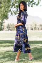Detail view of the mid-length sleeve with elastic cuff and ruffle neckline on the navy Lena Tiered Midi Dress, emphasizing construction.