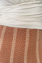 Side view of Astrid Midi Skirt highlighting A-line shape and mid-calf length in rust chevron knit fabric on model.