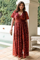 Back and sleeve detail of Veronica velvet maxi dress in rust, showing unlined flowy sleeves and skirt movement.