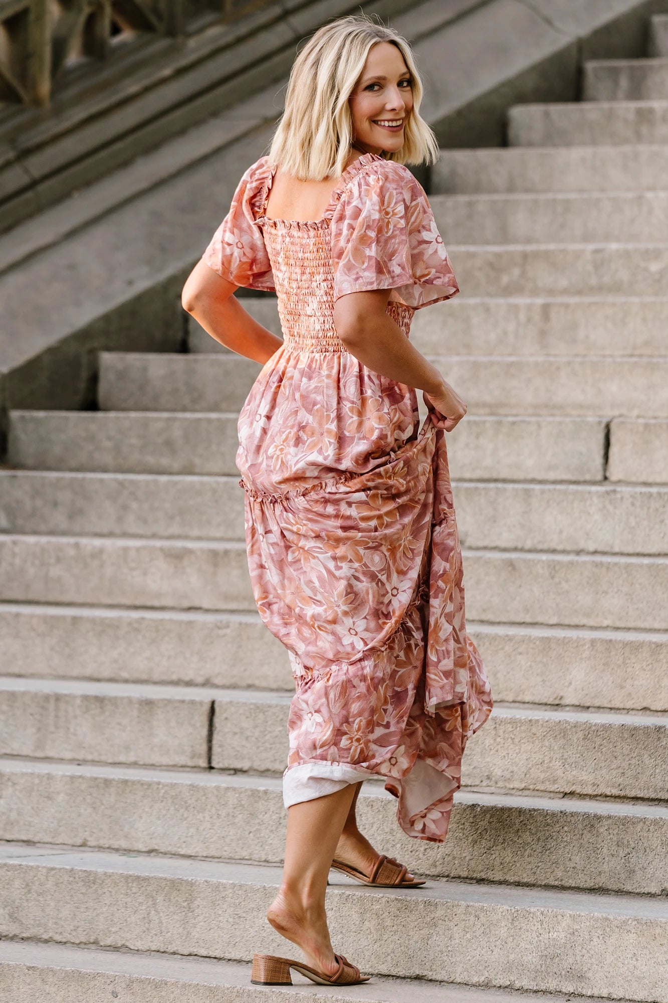 Model wearing the Southampton Smocked Maxi Dress in Dusty Mauve Floral featuring a square neckline, flutter sleeves with ruffle trim, a fully smocked bodice, and a flowing tiered maxi skirt with a dusty mauve floral print.