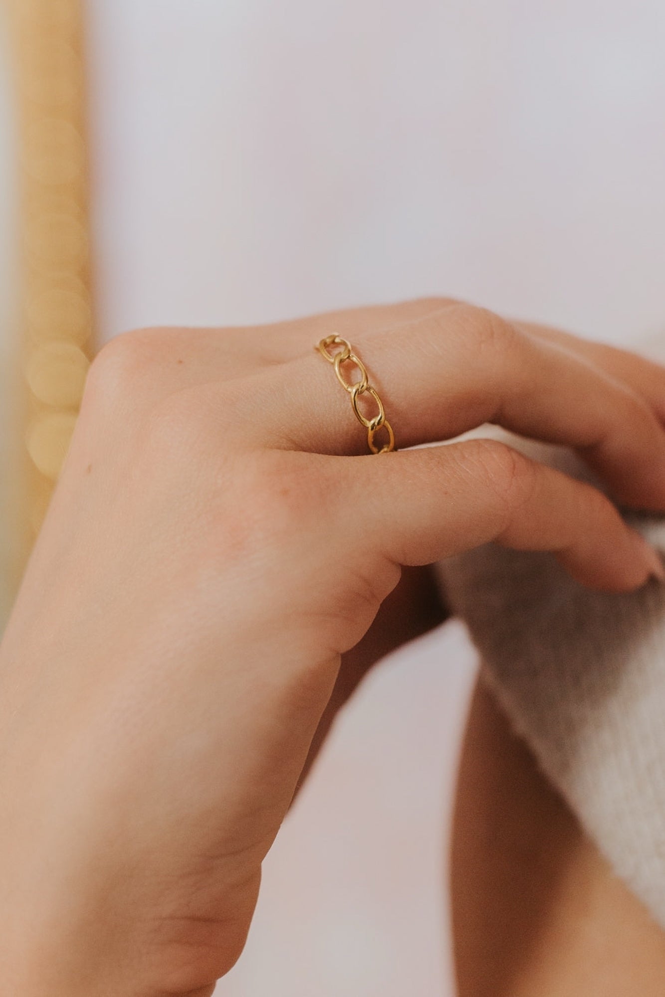 Side view of The Emma Ring highlighting the chain-link profile and polished 18K gold-plated finish against a soft background.