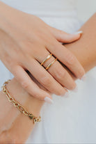 Close-up of Florence open-wave gold ring beside a bracelet on a neutral background, showing the ring's profile and polished finish.