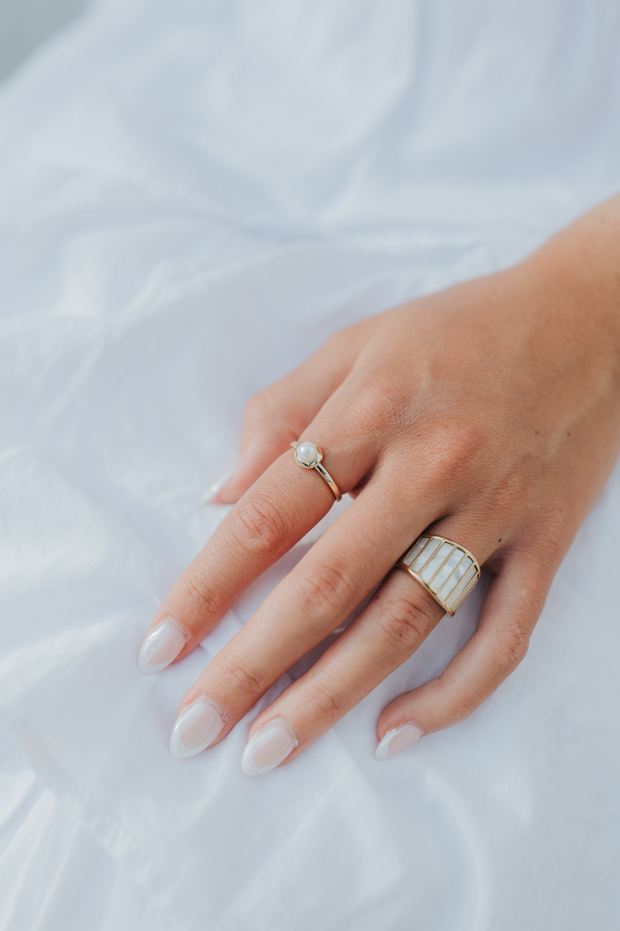 Model-style shot of the Alys ring worn on a finger, showing scale, vertical panel detail, and the ring's polished gold-tone finish.